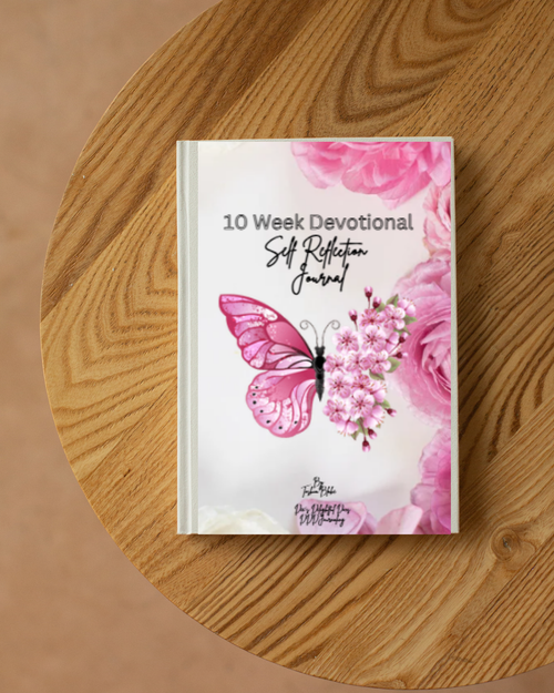 A 10 Week Devotional Self Reflection Journal with a pink butterfly and floral cover, displayed on a round wooden table.
